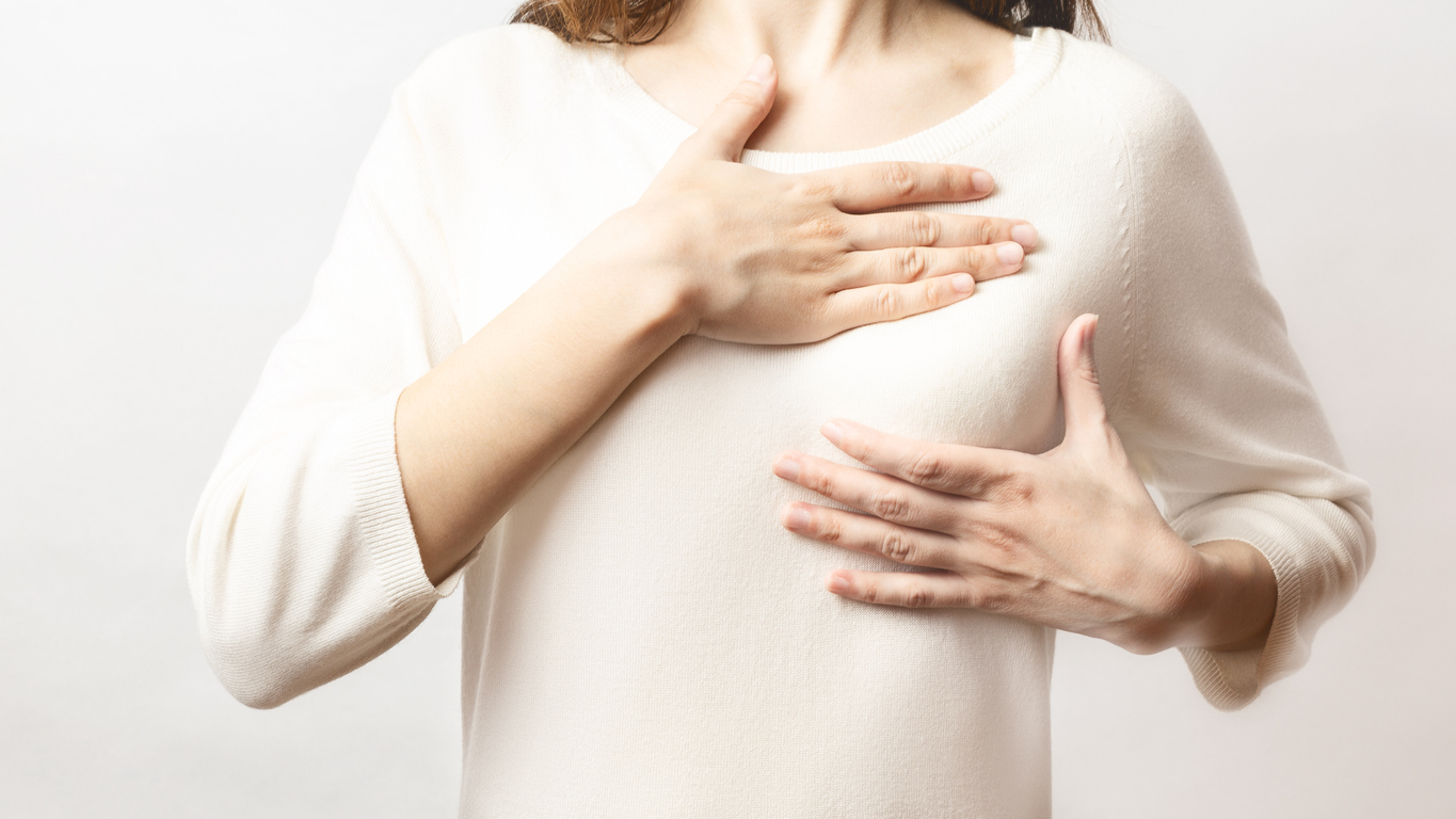 Woman hand checking lumps on her breast for signs of breast cancer